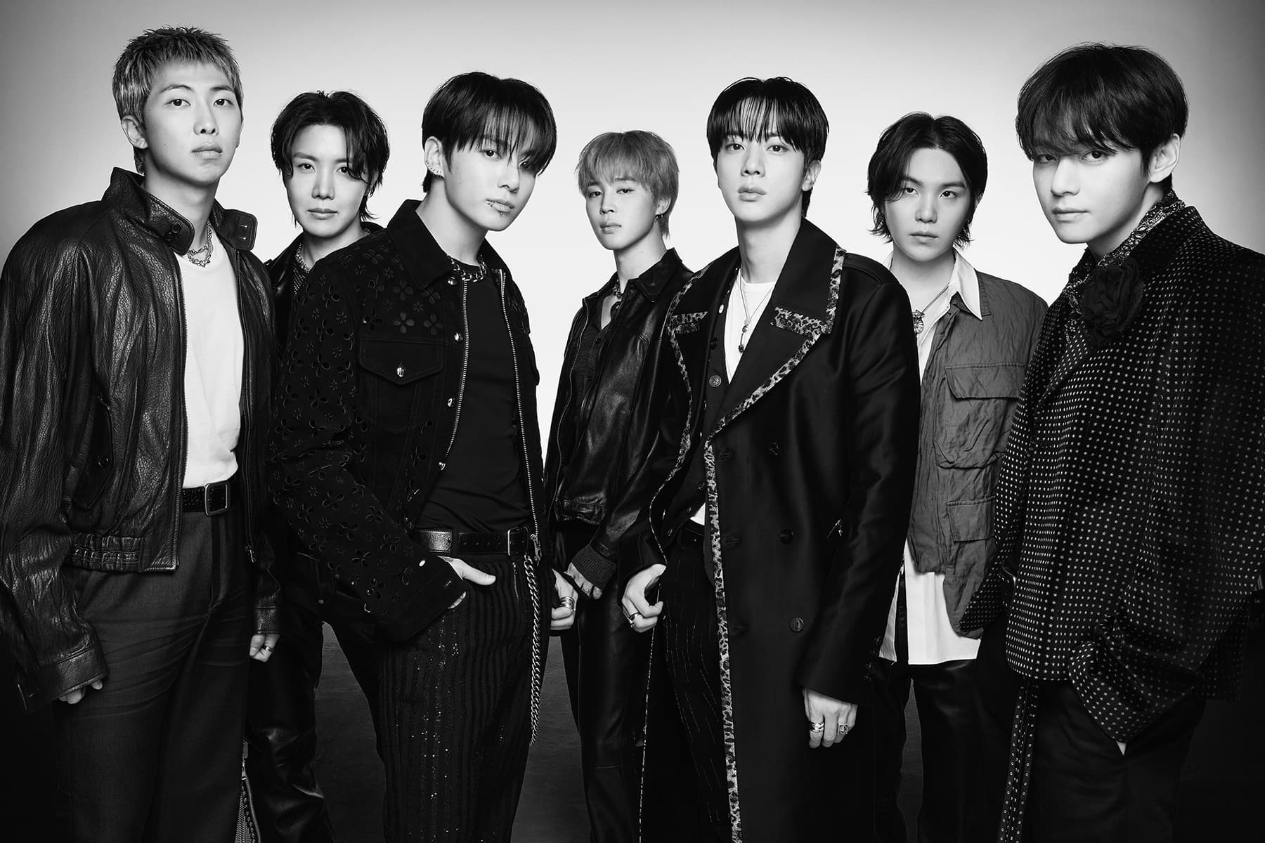Portrait du groupe BTS en tailleur, esthétique éditoriale sombre.